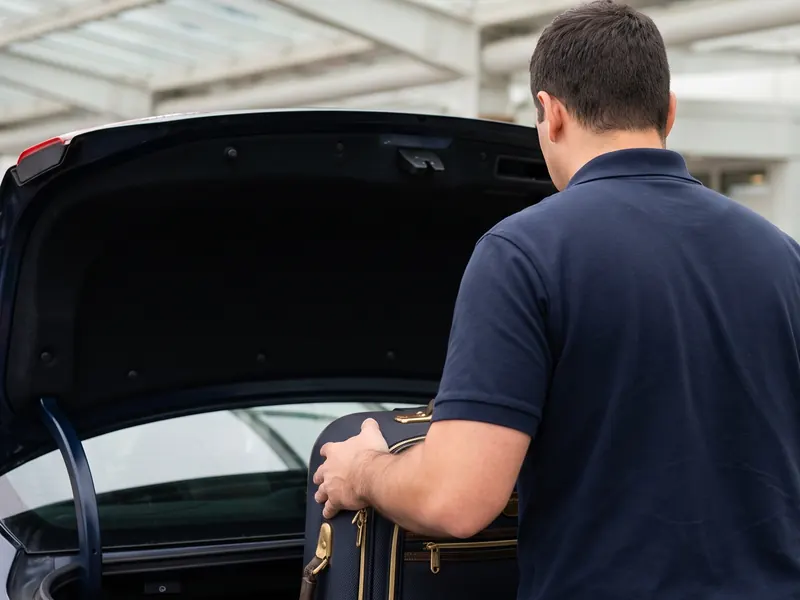 An airport drop-off, a suitcase lifted from the trunk